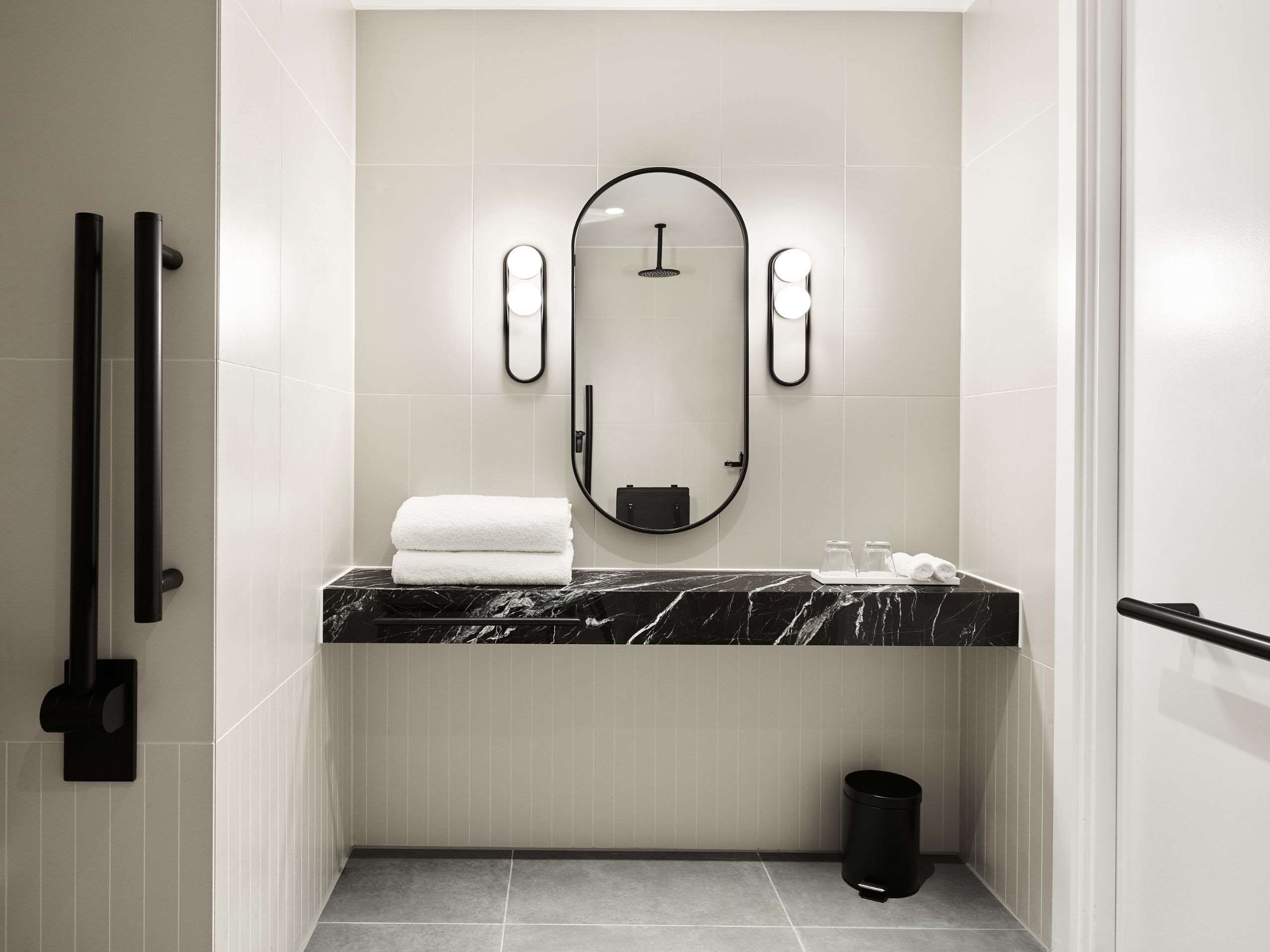 Un baño moderno con encimera de mármol, un espejo grande y dos dispensadores de toallas.
