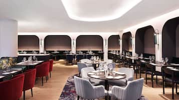 Un restaurant moderne avec des tables rondes, des chaises rouges et grises, et un espace de sièges central.