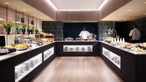 A modern buffet with a chef, wooden paneling, and a variety of food items. - Hyatt Regency London Stratford (London)