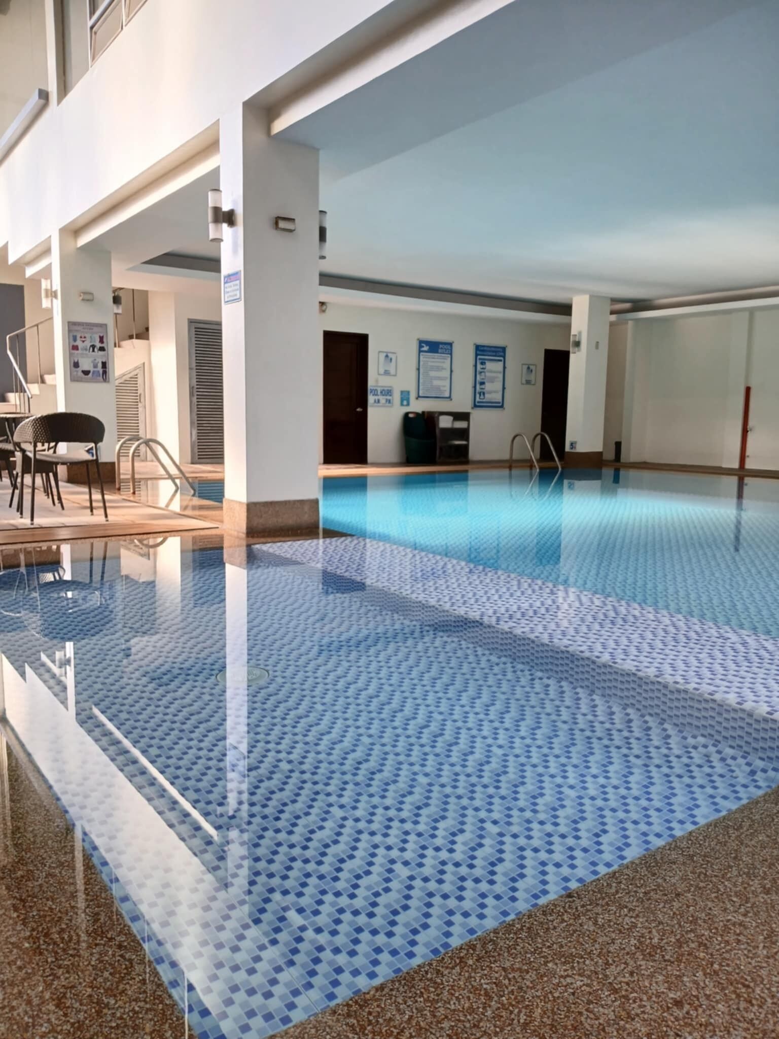 An indoor swimming pool with a blue tiled floor and a clear water surface.