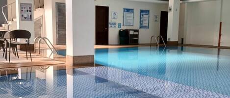 An indoor swimming pool with a blue tiled floor and a clear water surface.