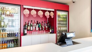 A bar area with a cash register, shelves of bottled beverages, and a refrigerated display. - Travelodge Farnborough Central (Farnborough)