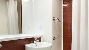 A bathroom with a white toilet, a sink, and a shower with a glass door. - Travelodge Farnborough Central (Farnborough)