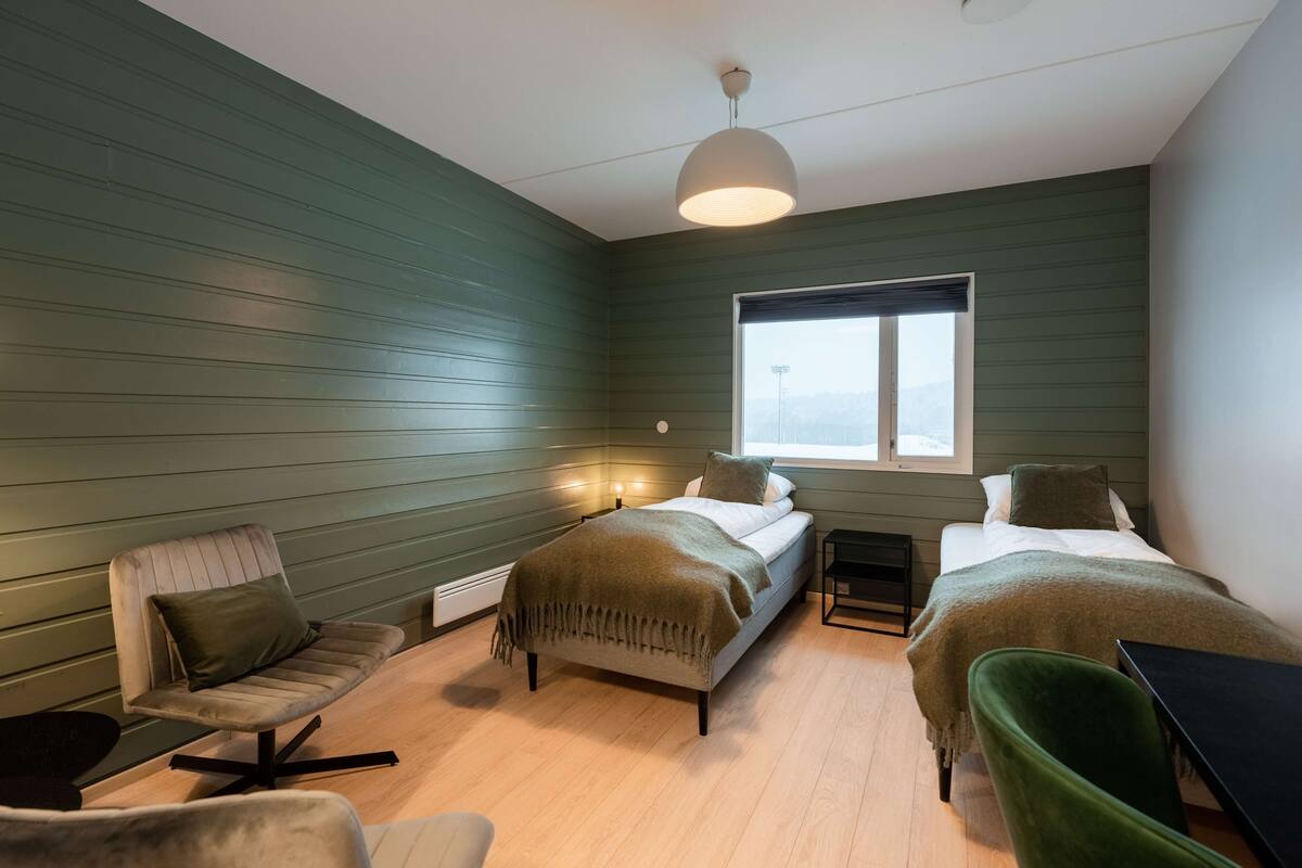 Une chambre avec deux lits, une chaise, une table et une fenêtre.
