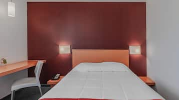 A hotel room with a bed, a desk, a chair, and two bedside lamps.