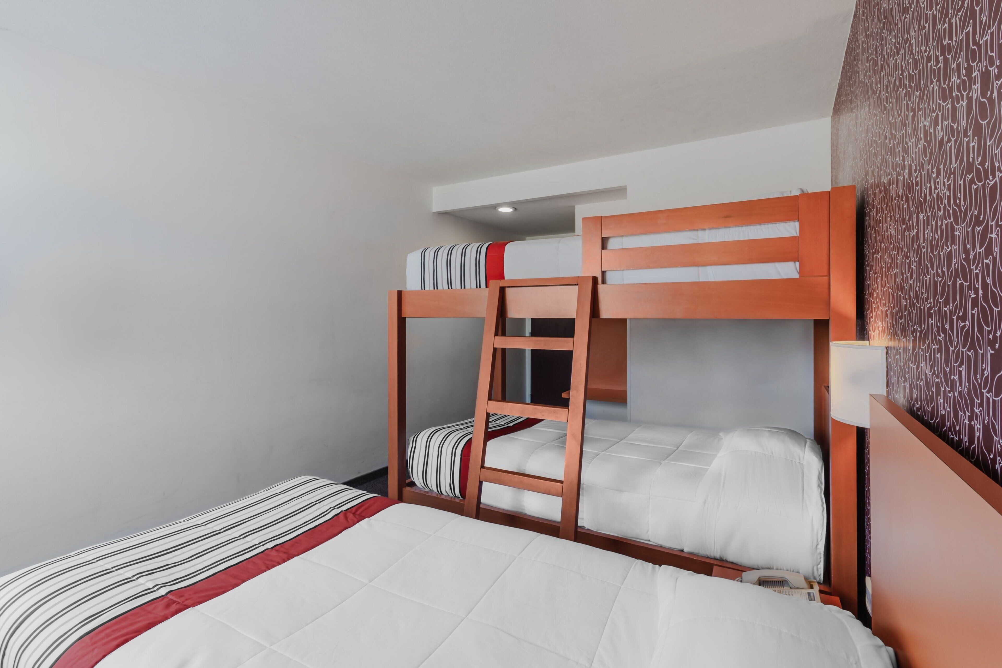 Habitación con literas, una mesita de noche y pared con diseño.