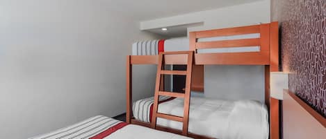 A bunk bed room with a ladder, a bedside table, and a patterned wall.