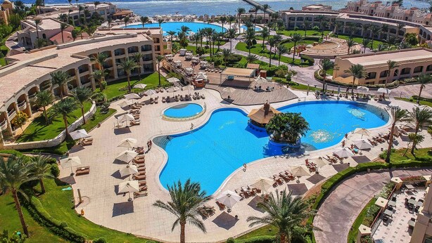 Een resort met diverse zwembaden, palmbomen en uitzicht op de oceaan.