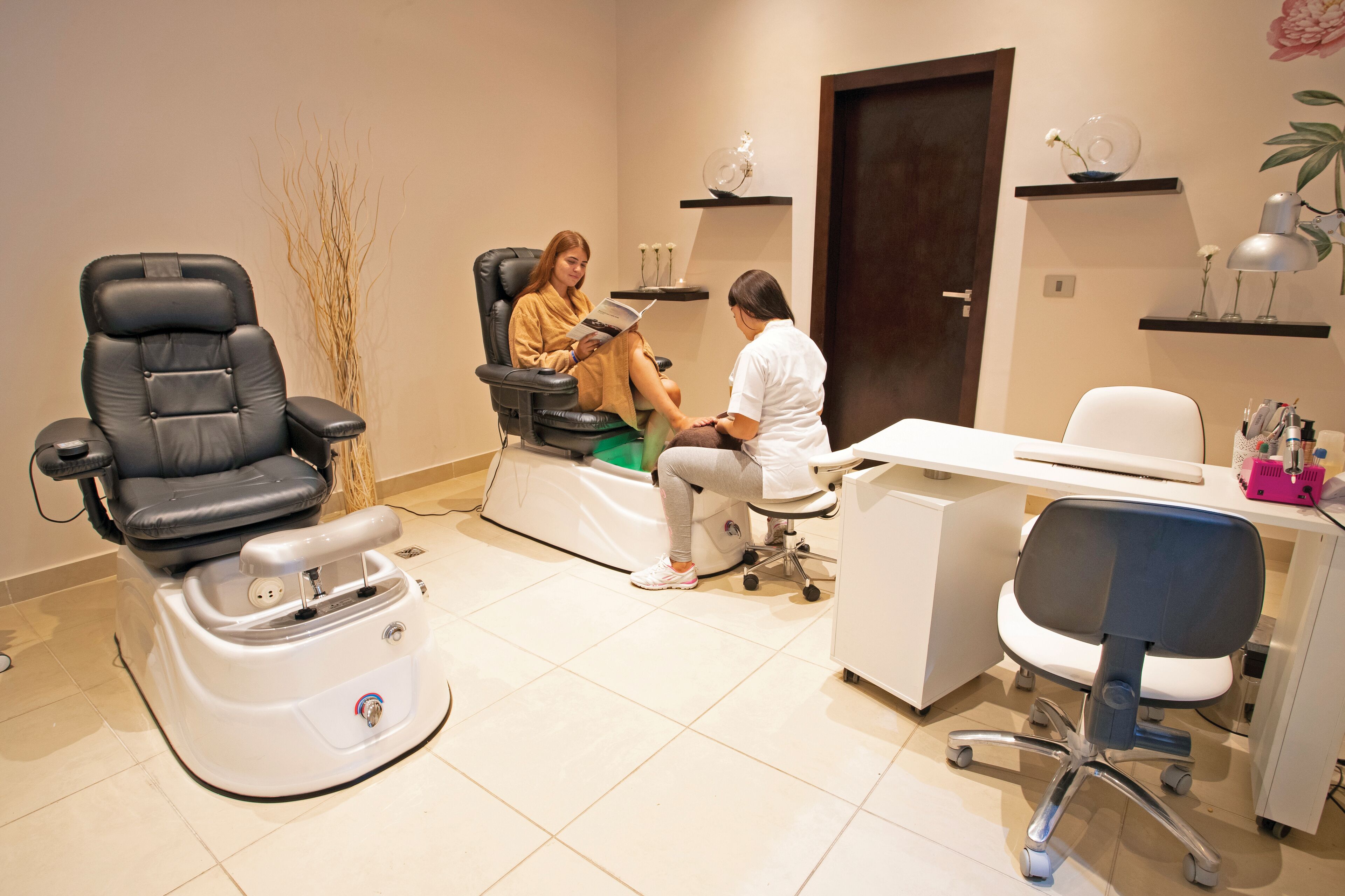 A medical examination room with a reclining chair, a treatment bed, and a desk with a computer.