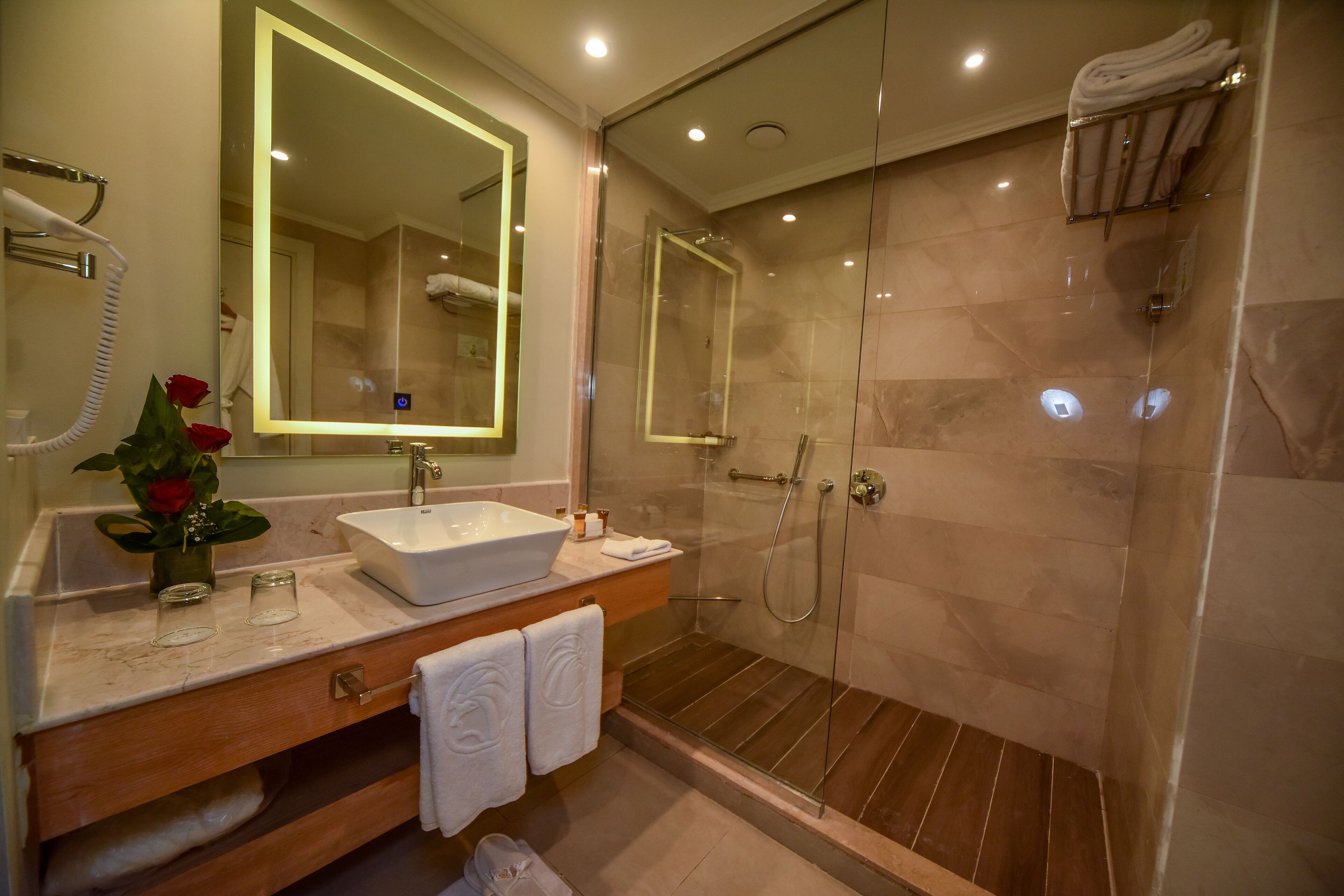 A modern bathroom with a large mirror, a sink, and a glass-enclosed shower.