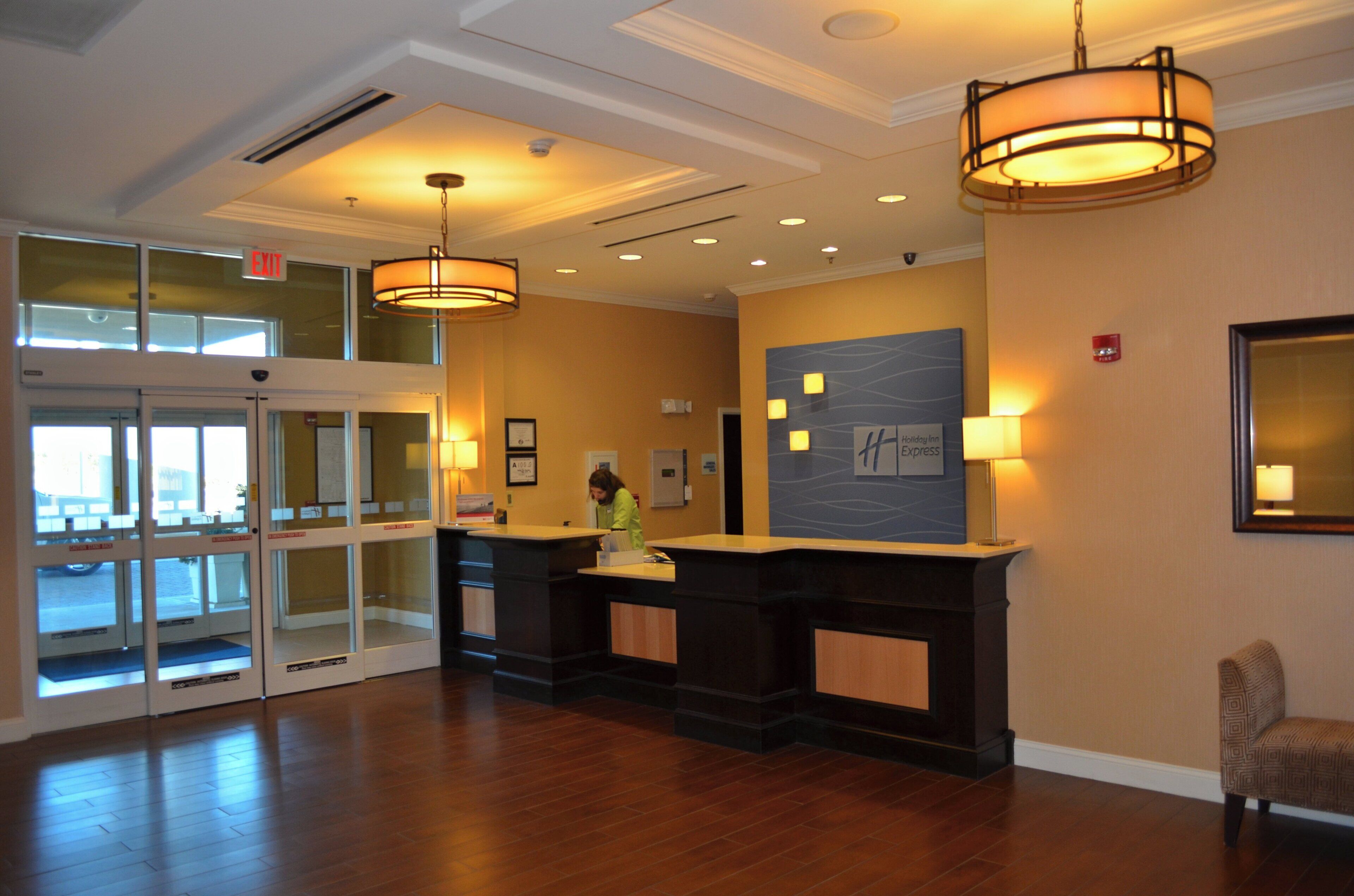 A hotel reception area with a glass door entrance, a reception desk, and a wall-mounted sign.