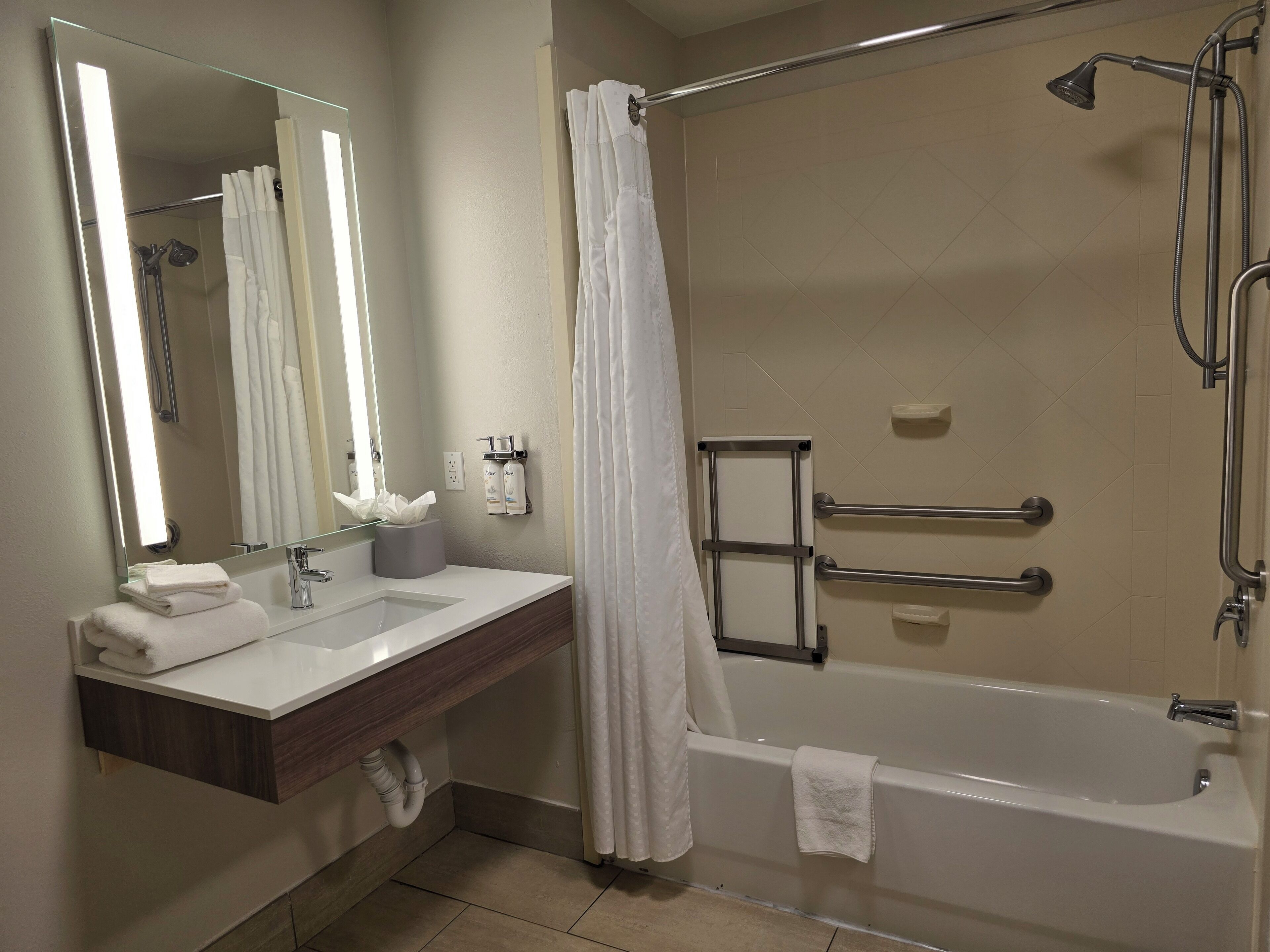 A modern bathroom with a shower, a bathtub, a vanity with a mirror, and a towel rack.