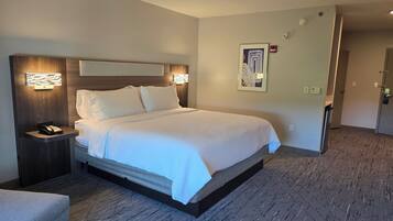 A hotel room with a large bed, a bedside table with a phone, and a wall-mounted light fixture.