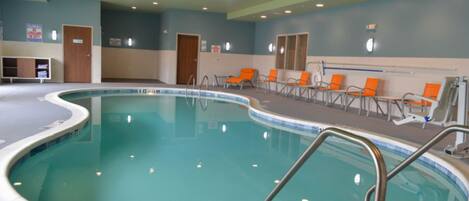 Una piscina interior de borde curvo, rodeada de sillones de descanso y una zona junto a la piscina.