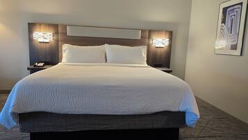 Una camera d'albergo con un letto grande, due comodini e una testiera con illuminazione integrata.