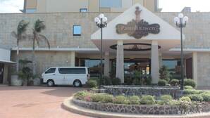 A hotel entrance with a sign reading "Pamunkey Hotel," a white van parked in front, and a landscaped area with plants and a stone wall. - Pamulinawen Hotel (San Nicolas)