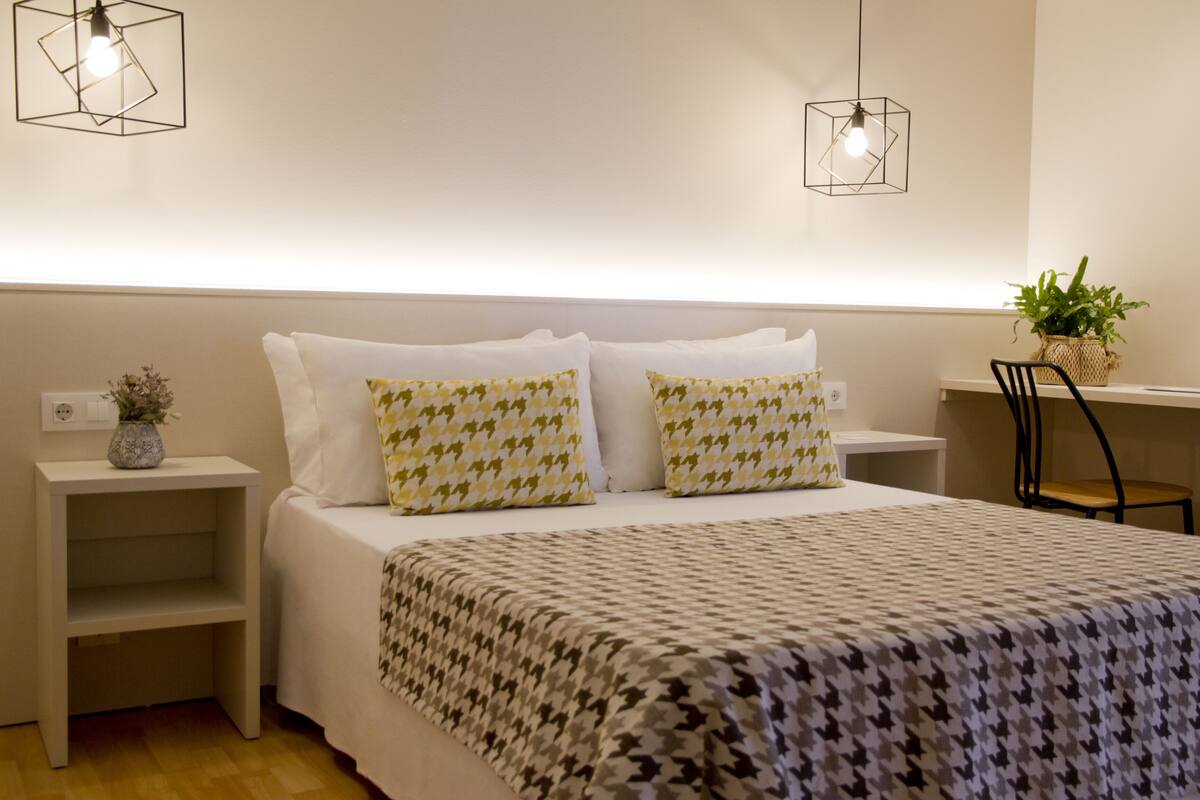 Une chambre à coucher bien rangée, avec un lit, deux tables de chevet, un bureau et une chaise.