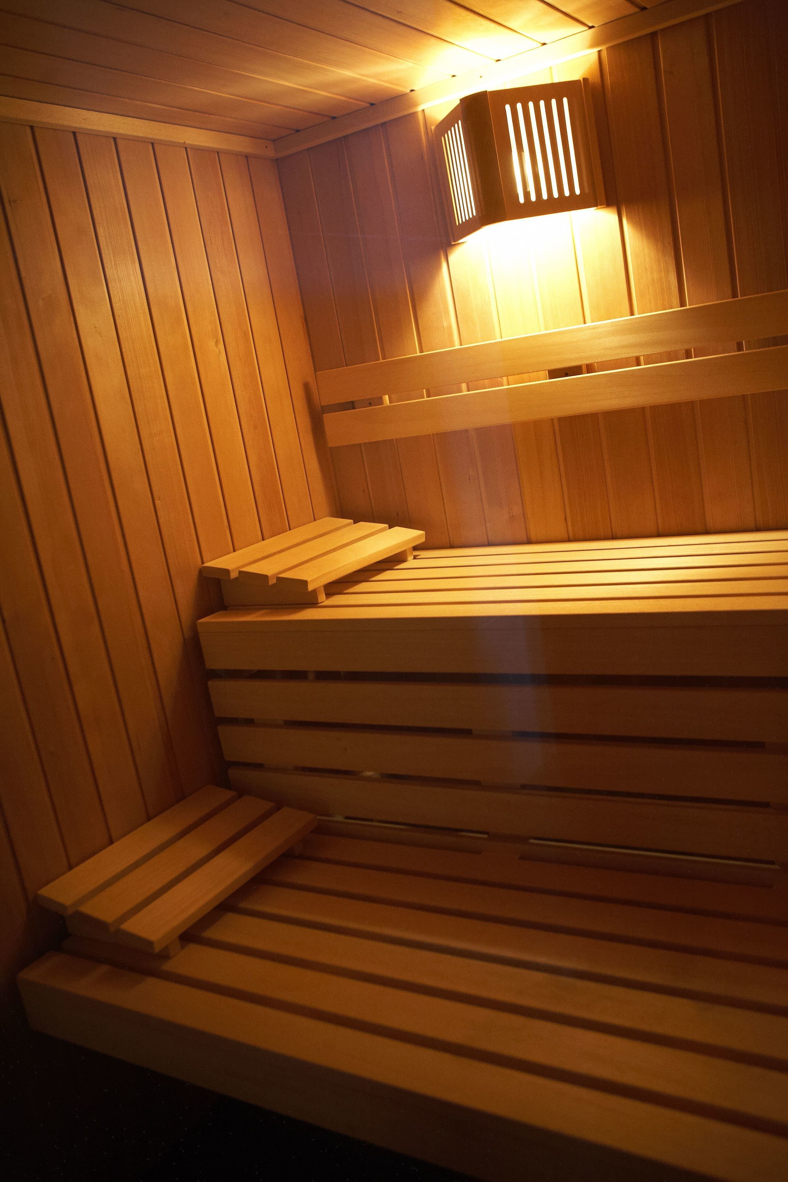 A wooden sauna bench with a slatted design, a bench seat, and a bench backrest.