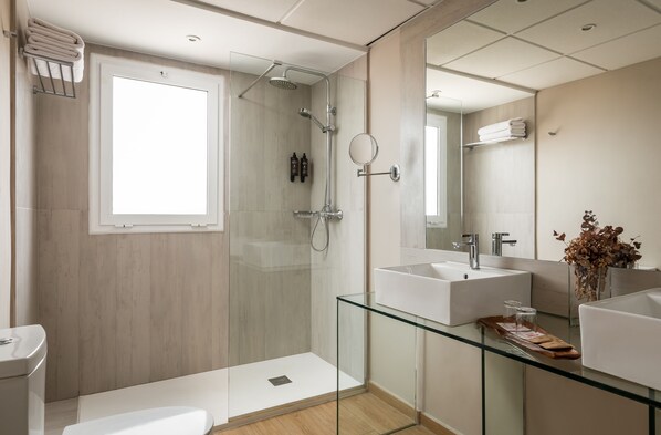A modern bathroom with a glass shower enclosure, two sinks, and a large mirror.