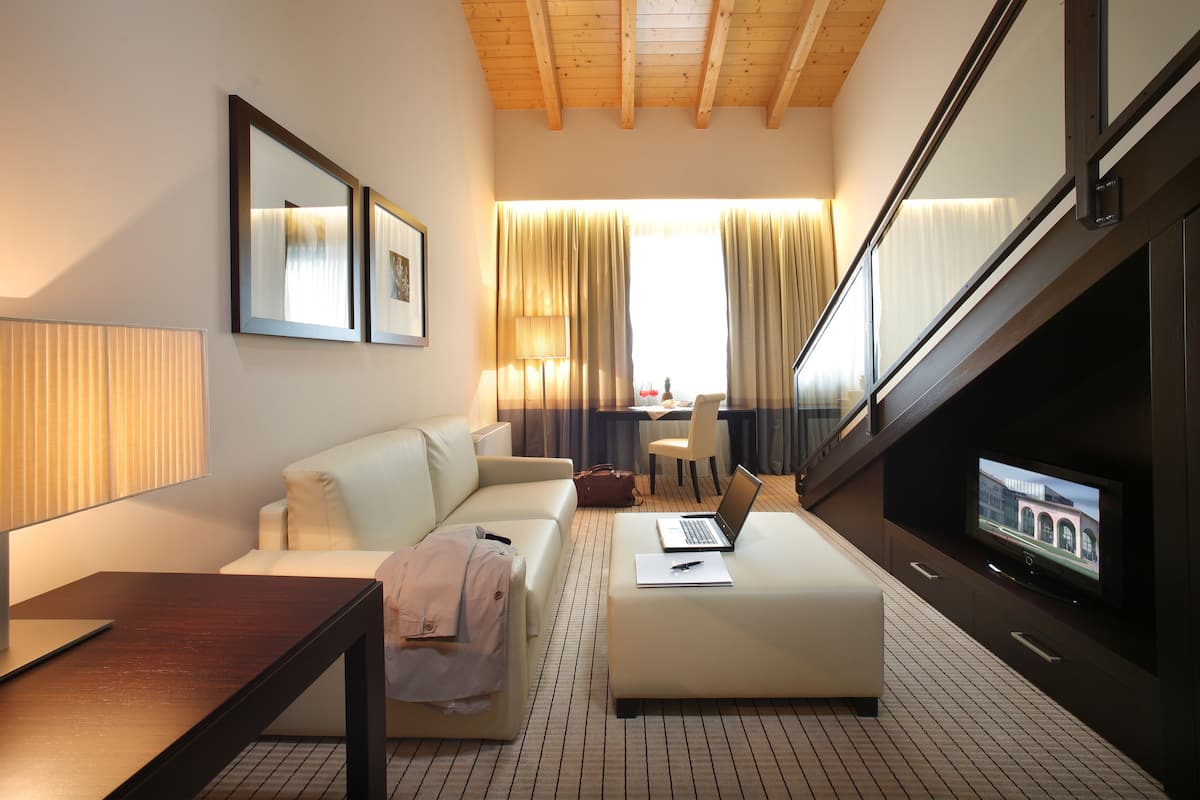 Une chambre d’hôtel moderne équipée d’un canapé, d’un bureau, d’un ordinateur portable et d’une télévision.