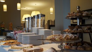 Een buffet met diverse gebakjes en desserts, waaronder croissants en taarten, gepresenteerd op een tafel met borden en bestek.