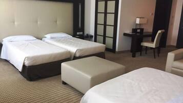 Habitación de hotel con dos camas, un escritorio, una silla y un amplio ventanal corredera.