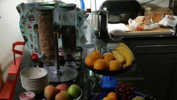 A kitchen counter with various food items, including fruits, cheese, and a carton of orange juice.