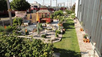 A well-maintained garden with a patio area, surrounded by a stone wall and various potted plants.