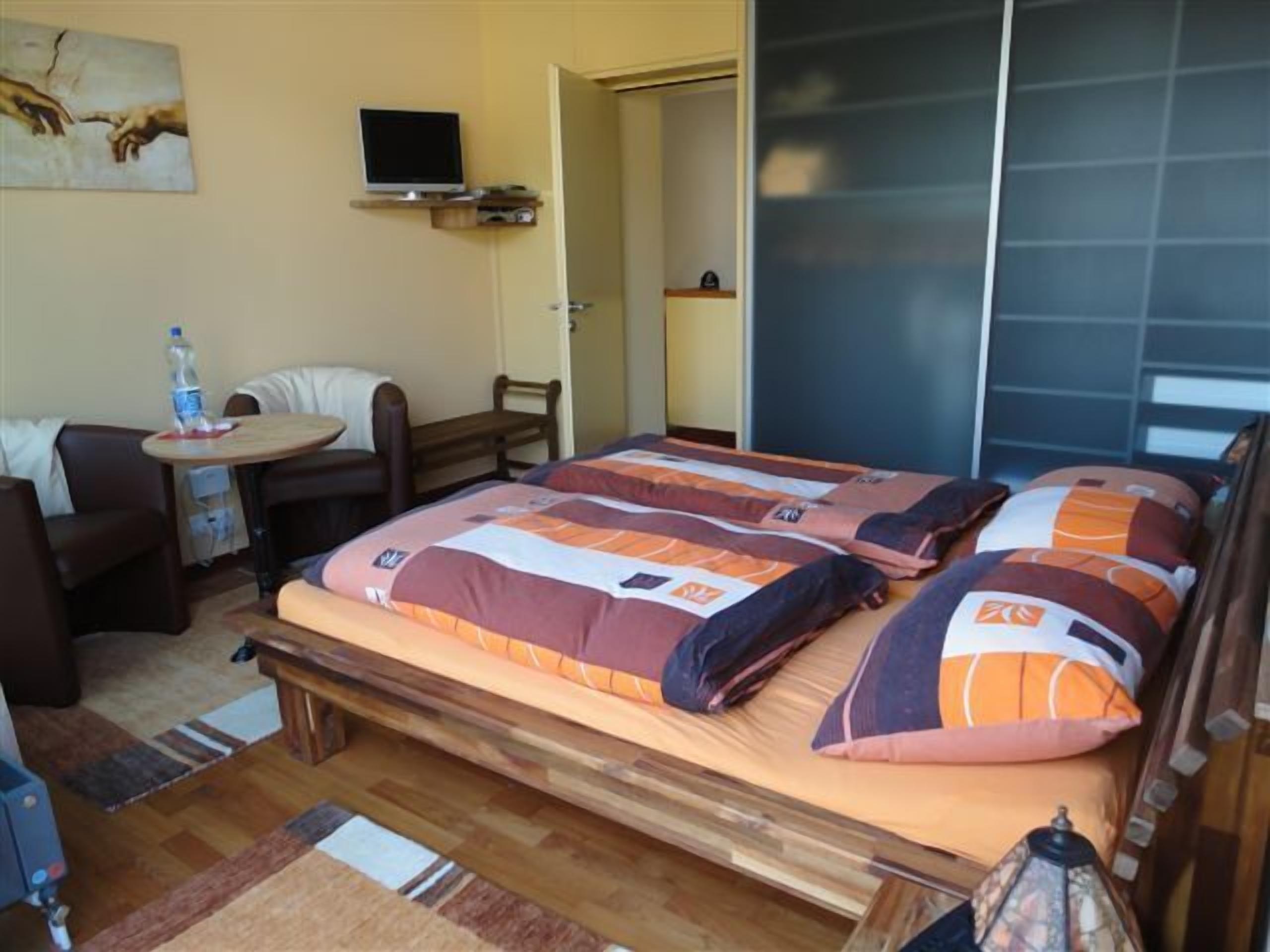 Une chambre à coucher avec un lit, un bureau, une chaise, une télévision et une porte.