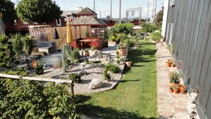 Un jardin bien entretenu, agrémenté d’un belvédère, de diverses plantes en pot et d’un chemin pavé de pierres.