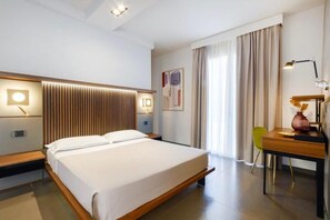 A modern hotel room with a large bed, bedside tables, a desk, and a chair. - Vespucci Hotel (Porto Cesareo)