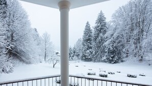 A snow-covered landscape with a balcony railing and a column. - hideauts hotels Der Rosengarten. (Fuessen)