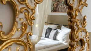 A room with a bed, a white curtain, and a gold-framed mirror. - hideauts hotels Der Rosengarten. (Fuessen)