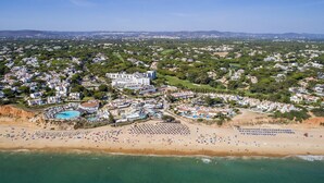 An aerial view of a coastal resort with a large beach, a swimming pool, and a hotel complex. - Encosta do Lago (Loulé)