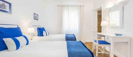 Ein Hotelzimmer mit zwei Betten, einem Schreibtisch und einem Sessel.