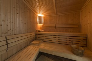 A sauna with wooden benches and a wooden bucket.