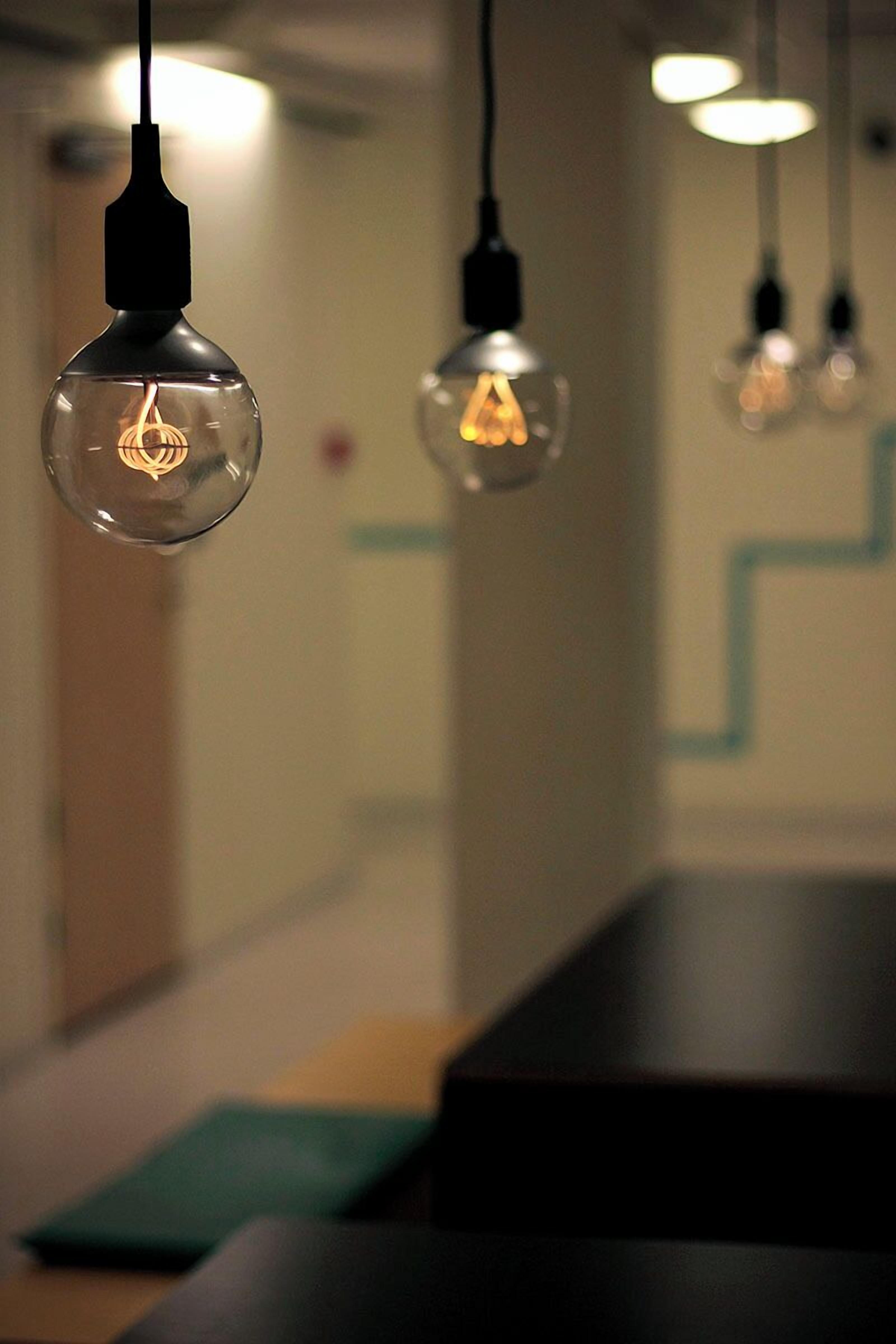 A modern interior with hanging pendant lights and a geometric wall design.