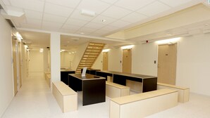 A modern, well-lit hallway with a staircase, multiple doors, and a reception desk area. - Citysleep - Hostel (Luleå)