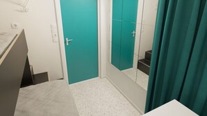 A bathroom with a teal door, a mirror, a sink, and a shower area. - Citysleep - Hostel (Luleå)