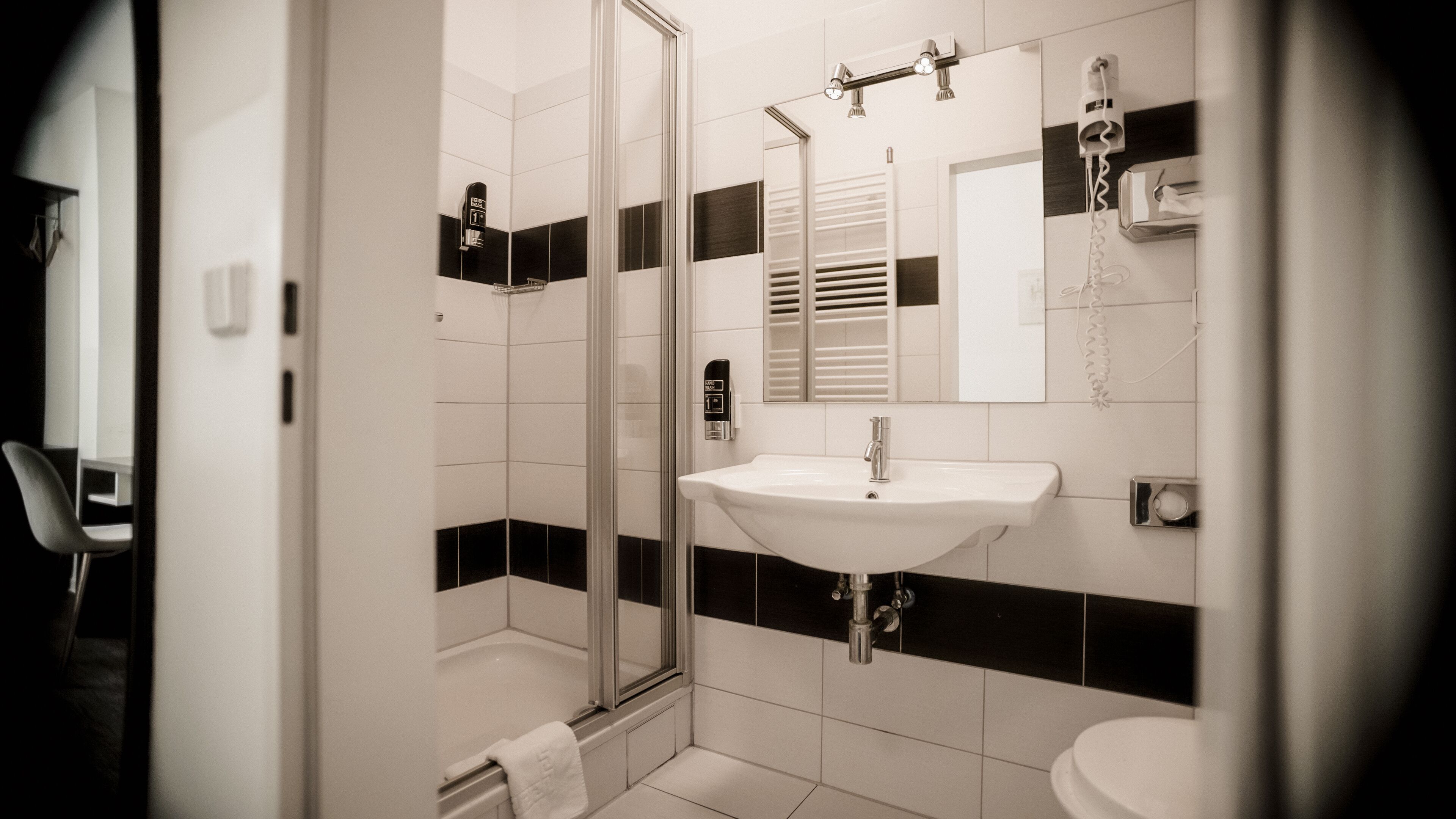 Ein modernes Badezimmer mit Glasdusche, Waschbecken in Weiß und einem Spiegel.