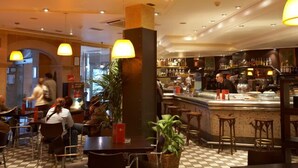 Un restaurant avec un sol à carreaux, des lampes suspendues et un coin bar avec des tabourets.