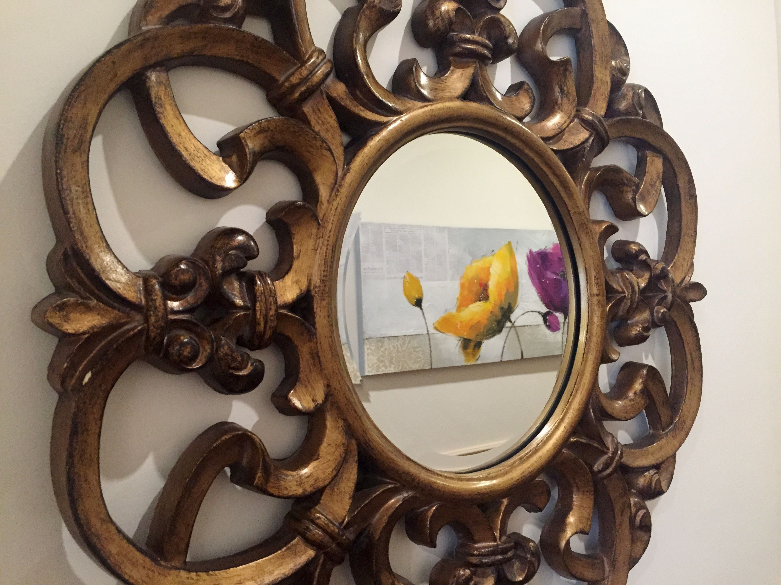 Een spiegel met een sierlijk houten frame.