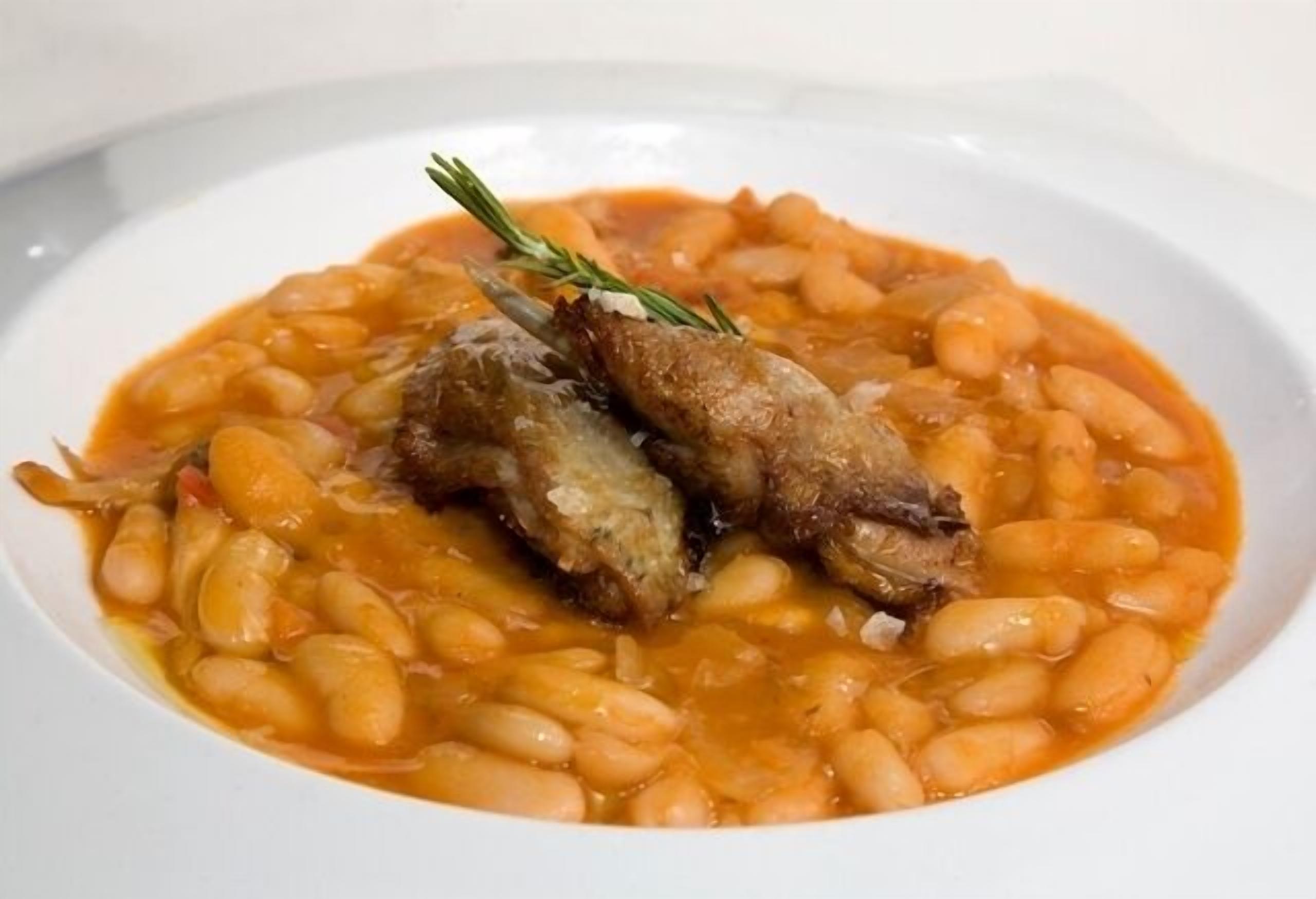 Eine Schüssel Bohnen mit Fleisch und einem Rosmarinzweig.