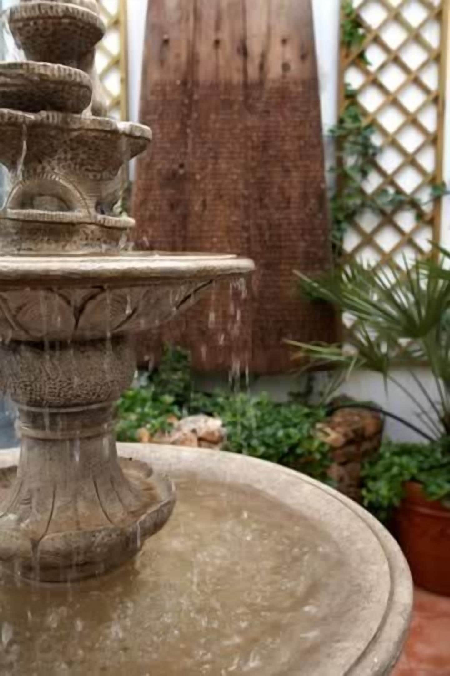 A stone fountain with multiple tiers and water flowing from the top tier.
