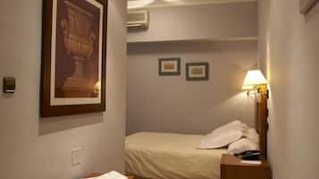 Un dormitorio con cama, mesita de noche, cómoda de madera, un cuadro en la pared y luces empotradas en el techo.