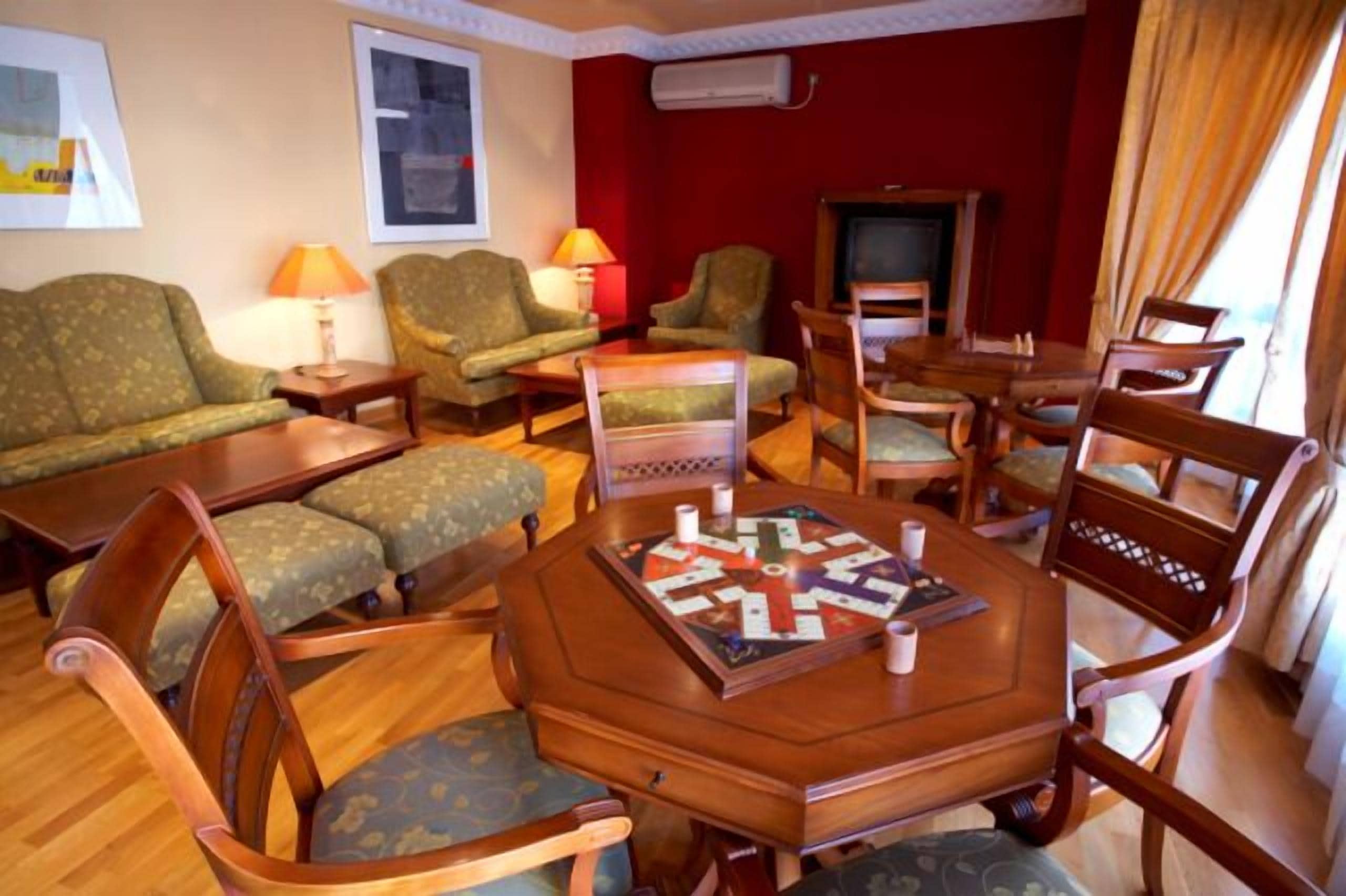 A cozy living room with a wooden coffee table, green patterned sofas, and a television.
