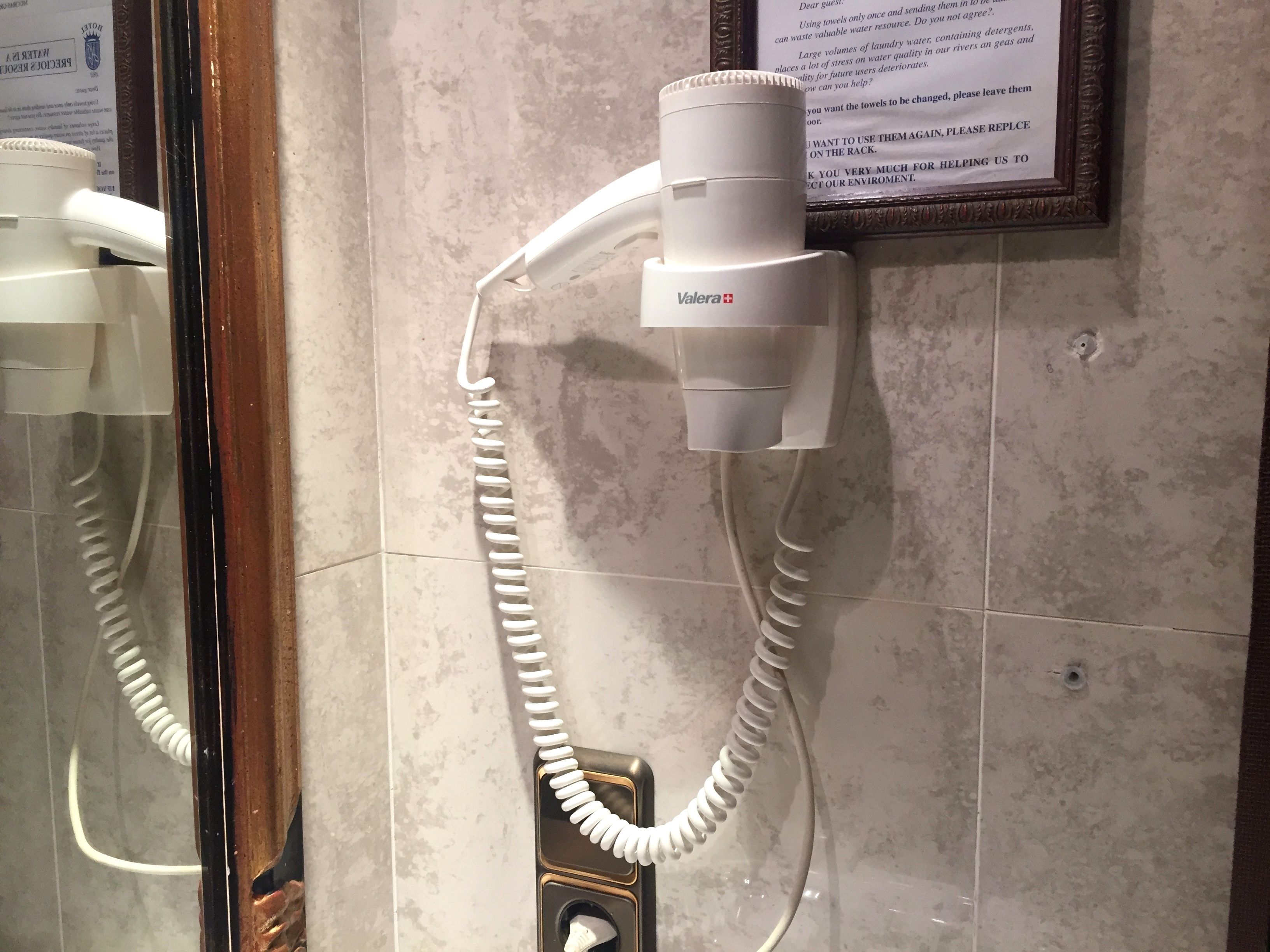 A Valera hairdryer mounted on a wall with a coiled cord.