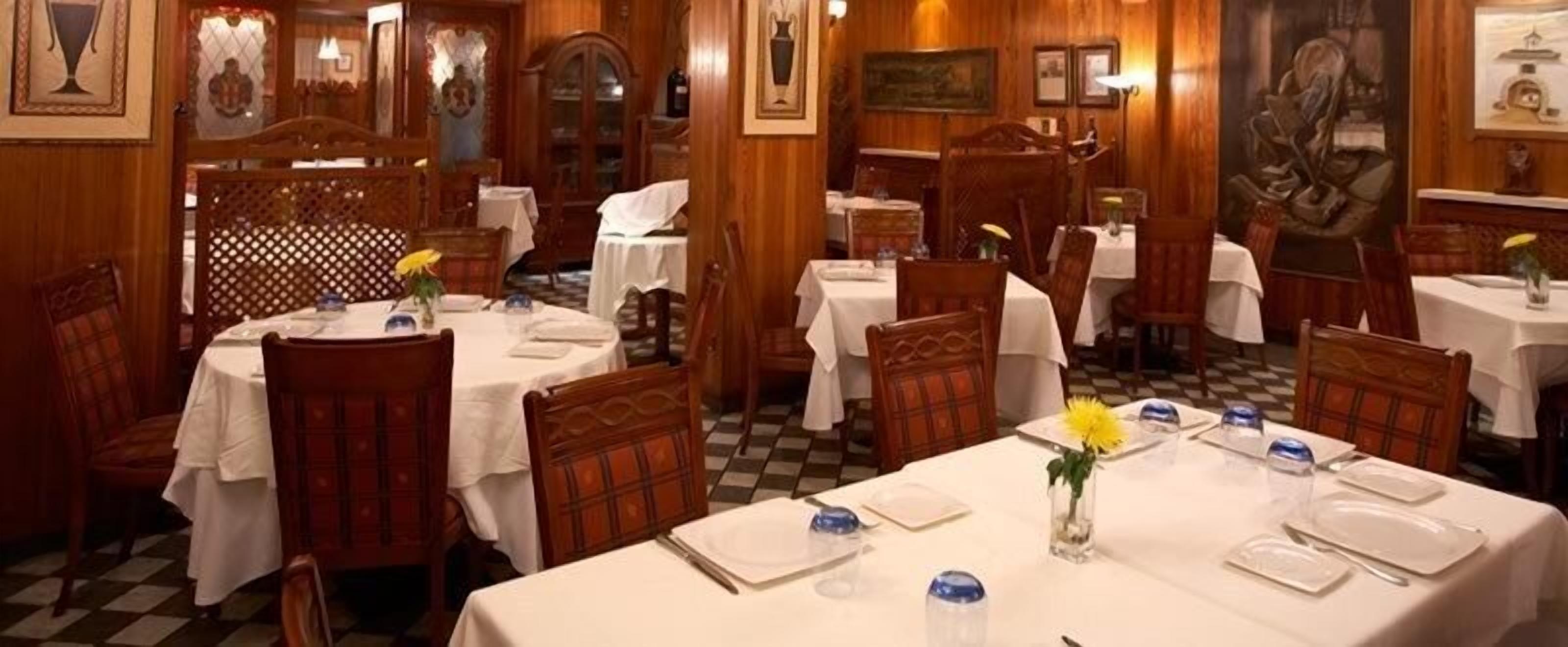 A restaurant with wooden decor, white tablecloths, and a checkered floor.