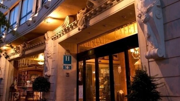 La façade d’un hôtel présente une architecture classique, avec notamment des colonnes richement décorées et une entrée monumentale.
