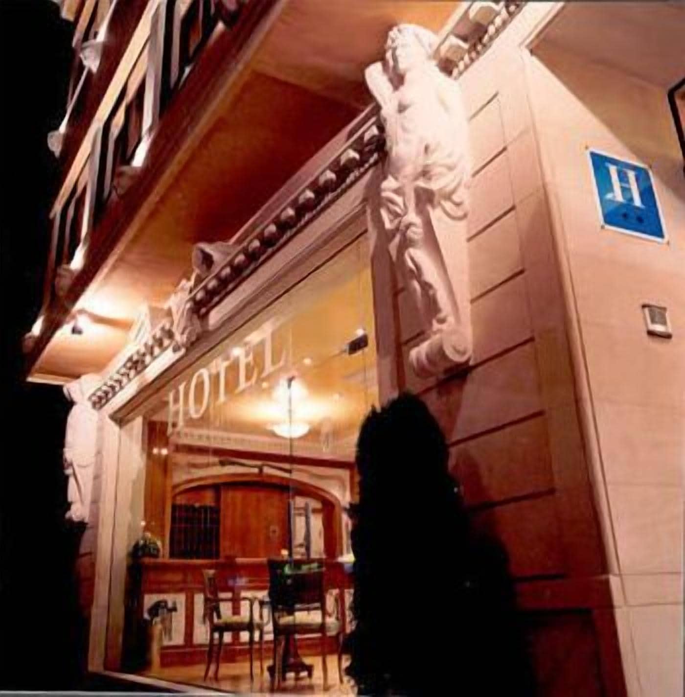 A hotel entrance with a large statue, a reception desk, and a blue handicap accessibility sign.